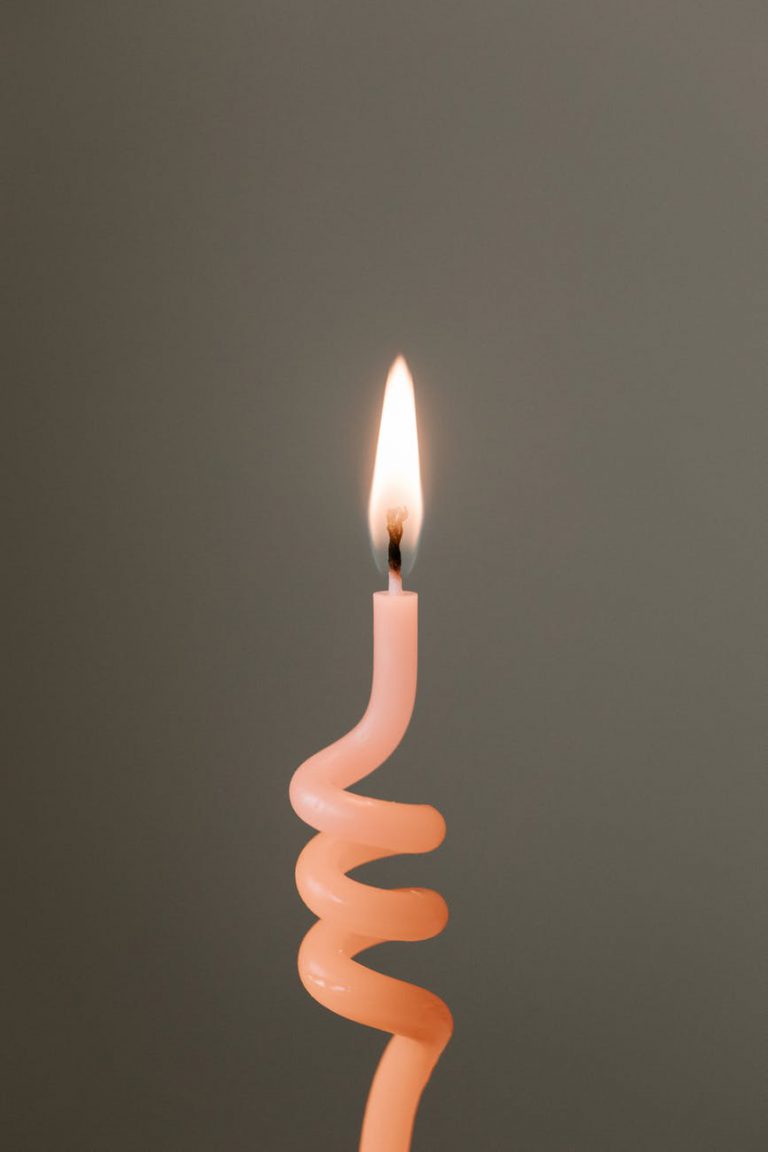 burning pink candle against gray background